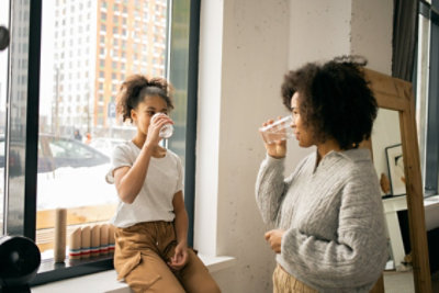 mother and daughter drinking water near the window