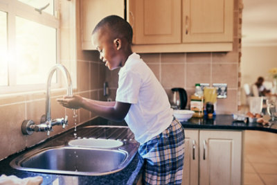 boy washing hands at kitchen sink
