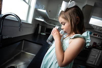 little girl drinking water at sink