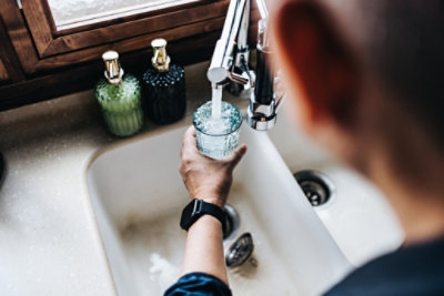 man filling glass at kitchen faucet
